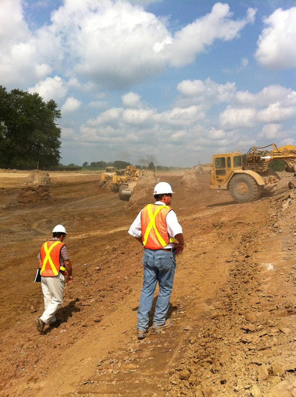 Two crew members in white safety hats on an excavation site.